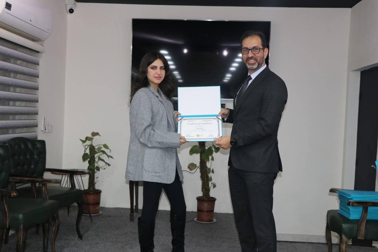 head of Rewaq Baghdad Center for Public Policy, MR. Abbas Al-Anbouri, awards a group of students from the Translation Department at Al-Mustansiriya University certificates of appreciation.